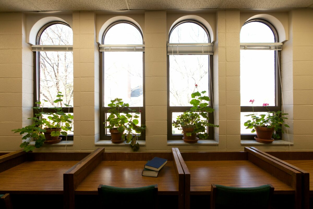 Empty study carrels in Wheaton Buswell Library with arched windows and geraniums