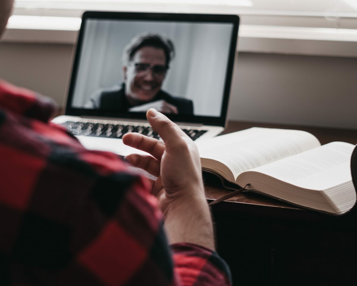 Two men talking through a video call on a laptop