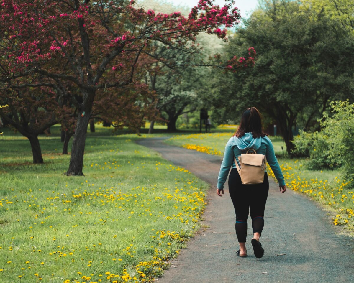 A photo of a woman walking on a road with a backpack