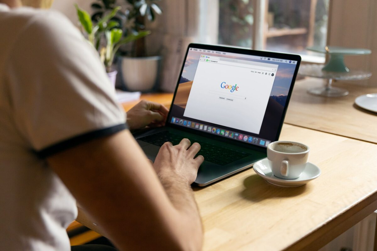 A man sitting at a laptop with Google open